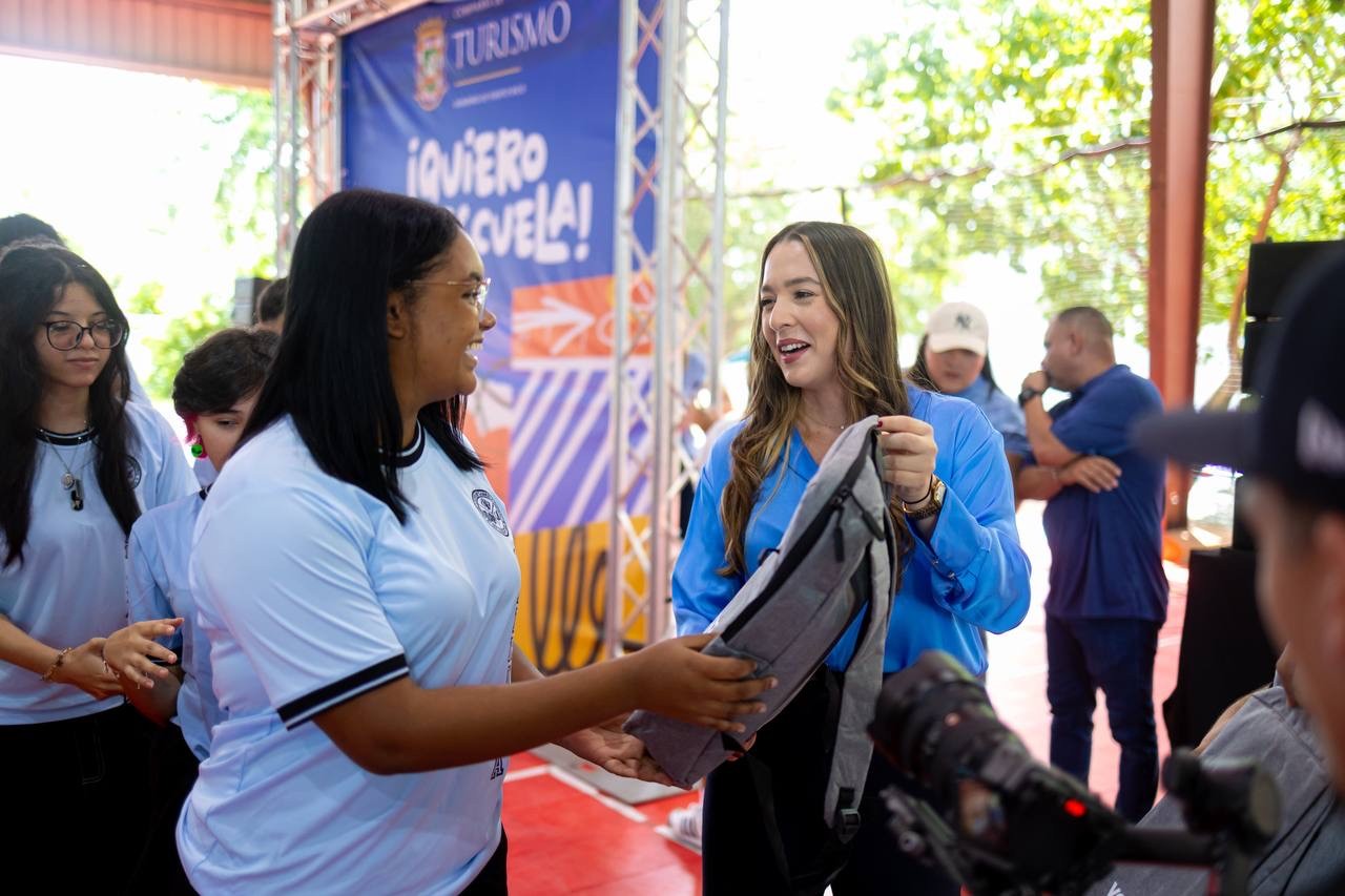 La directora ejecutiva de la Compañía de Turismo de Puerto Rico, Willianette Robles Cancel, hace entrega de materiales escolares a una estudiante de la Escuela Gabriela Mistral.